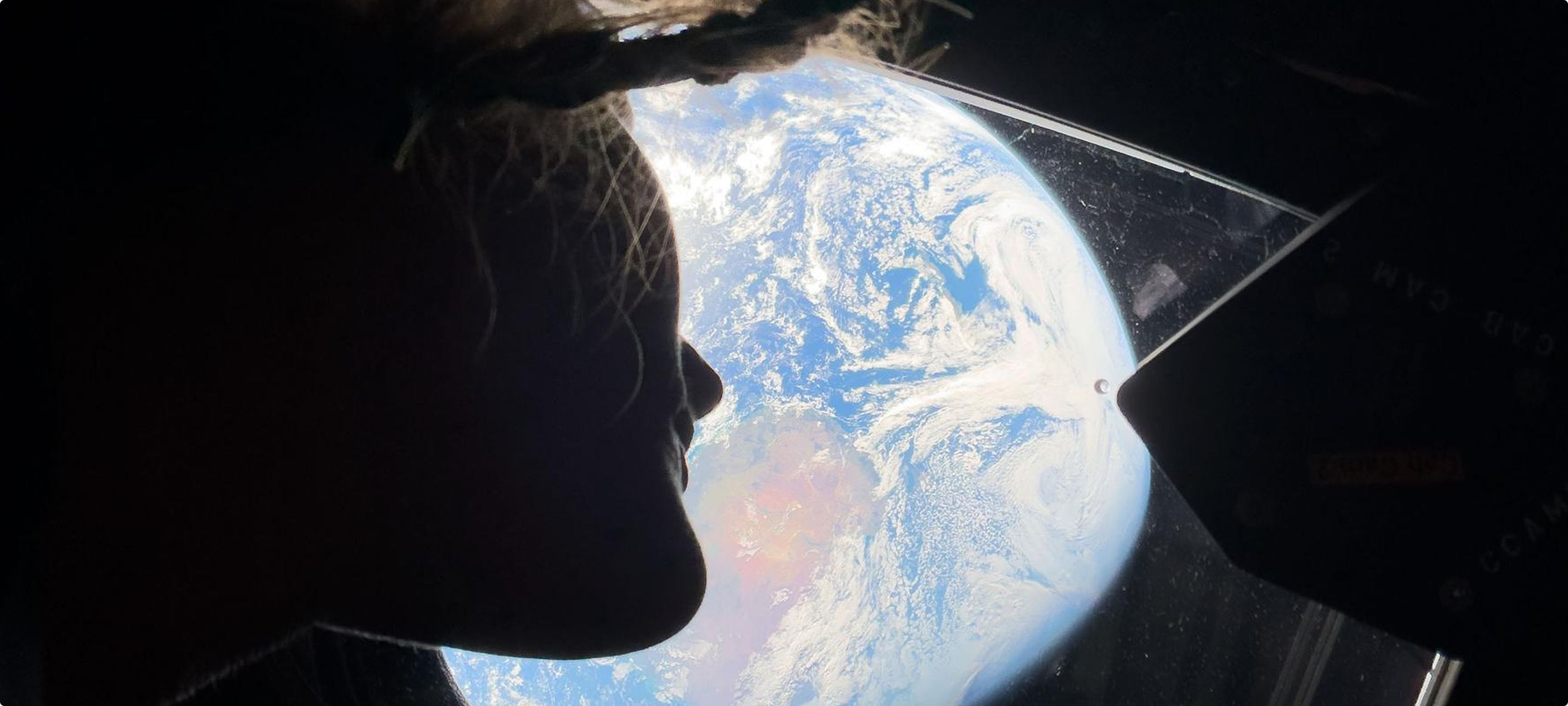 Silhouette of a face against a window onto Earth from orbit